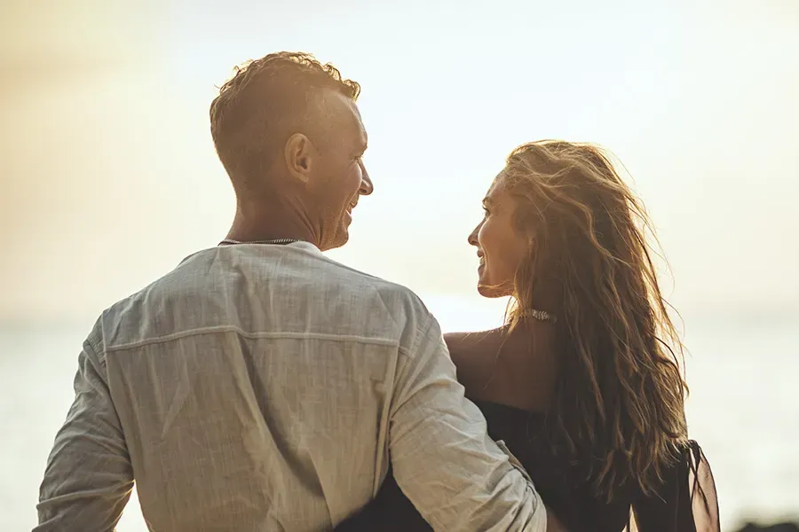 Anti-Aging-Clinic A couple gazes at each other on the beach at sunrise, viewed from behind. Schedule Anti-Aging treatment from Christine Collins, MD in Westside/Beverly Hills.