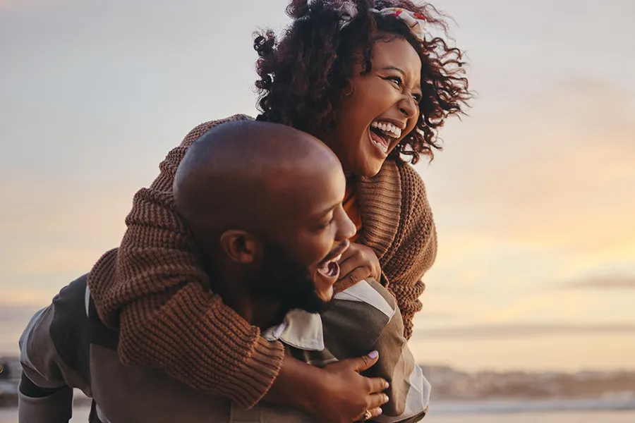 BCAA-Vitamin-Injection-Clinic A middle-aged Black couple embrace playfully at the beach. Schedule BCAA Vitamin Injection treatment from Christine Collins, MD in Westside/Beverly Hills.
