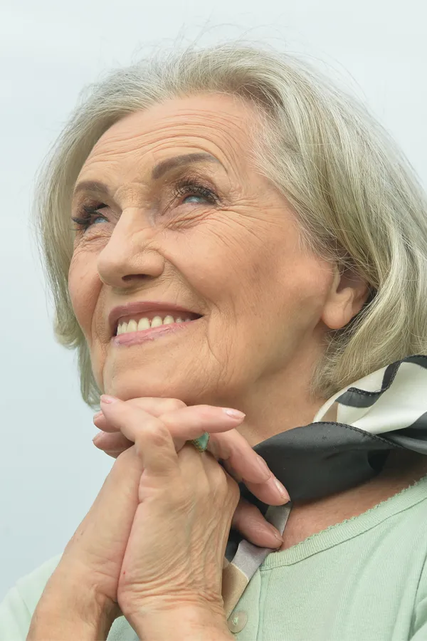 Hot-Flashes-and-Night-Sweats-Treatments An older woman holds her hands together under her chin and looks up at a cool sky smiling. Get treatment for hot flashes and night sweats from Christine Collins, MD in Westside/Beverly Hills.