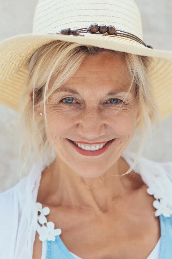 MonaLisa-Touch-Vaginal-Rejuvenation-Clinic A cheerful middle-aged woman with curly hair, leaning on her hand, smiling broadly and looking off to the side after receiving MonaLisa Touch Vaginal Rejuvenation treatment by Christine Collins, MD in Westside/Beverly Hills.