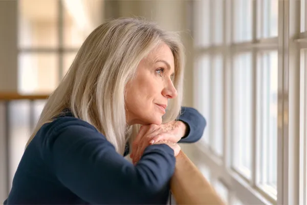 PMDD-Specialist A middle-aged woman with with a somber expression stares out the window. Get treatment for Premenstrual Dysphoric Disorder from Christine Collins, MD in Westside/Beverly Hills.