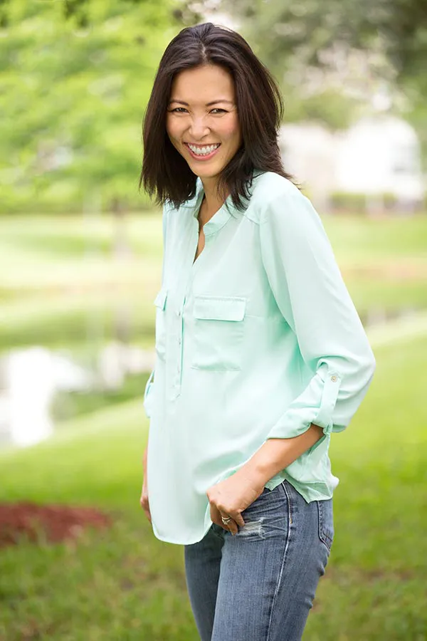Perimenopause-Treatment A middle-aged brunette woman in a light green button-up shirt stands outside smiling, happy with her perimenopause treatment from Christine Collins, MD in Westside/Beverly Hills.