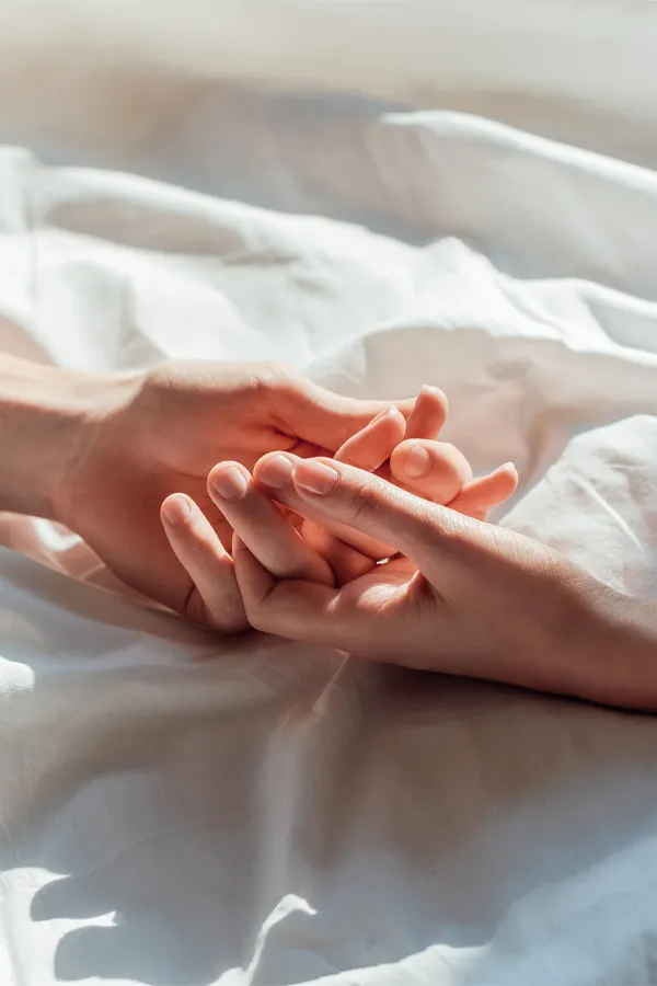 STD-Testing-Treatment Hands clasping on top of sheets. Get STD testing from Christine Collins, MD in Westside/Beverly Hills.