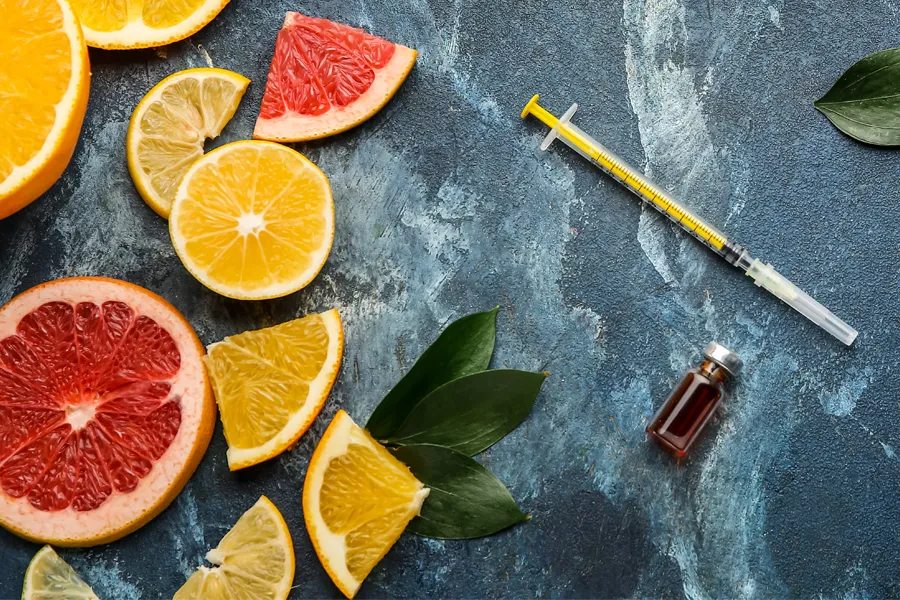 Vitamin-Injection-Doctor A gray marble countertop covered with sliced fruit and a syringe and vial, representing vitamin injections from Christine Collins, MD in Westside/Beverly Hills.